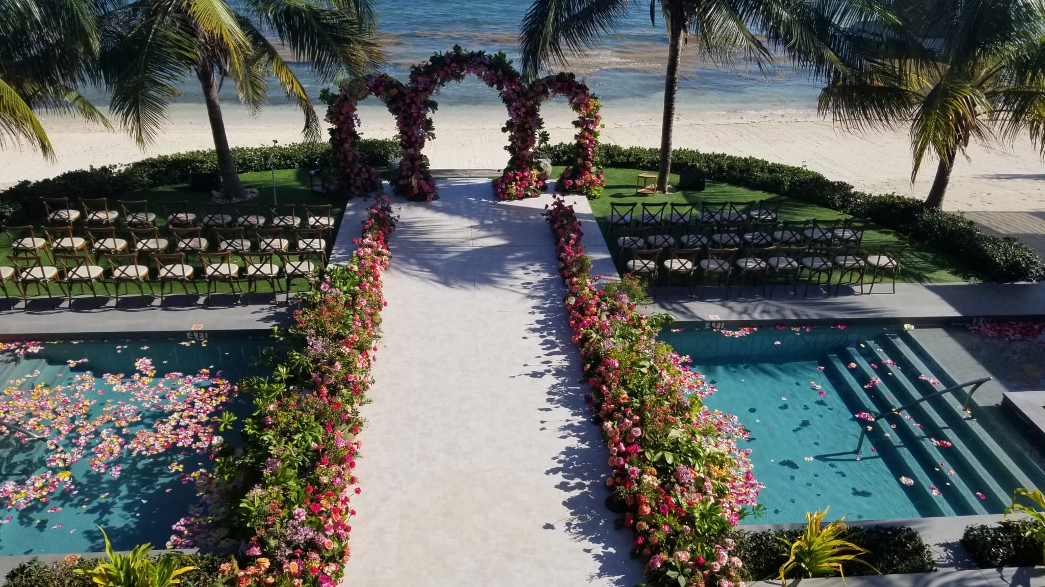 Colorful outdoor wedding ceremony setup with three vibrant arches.