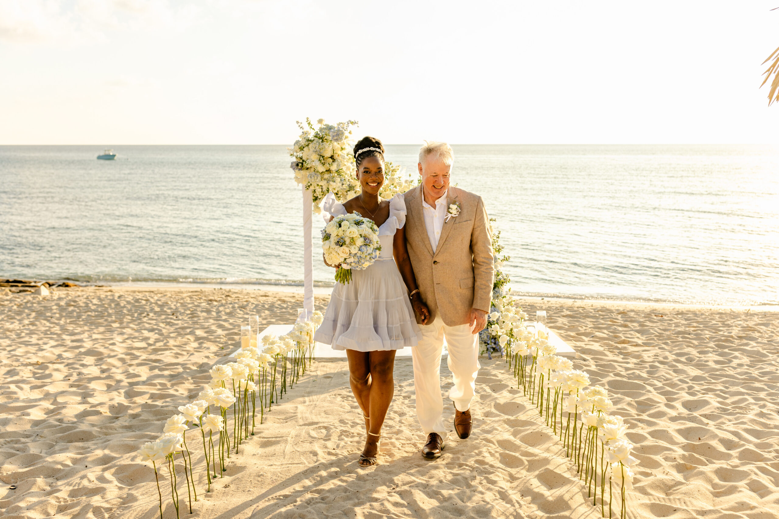 Lory Ann and Eugene strolling together on white sand beach during their vow renewal celebration