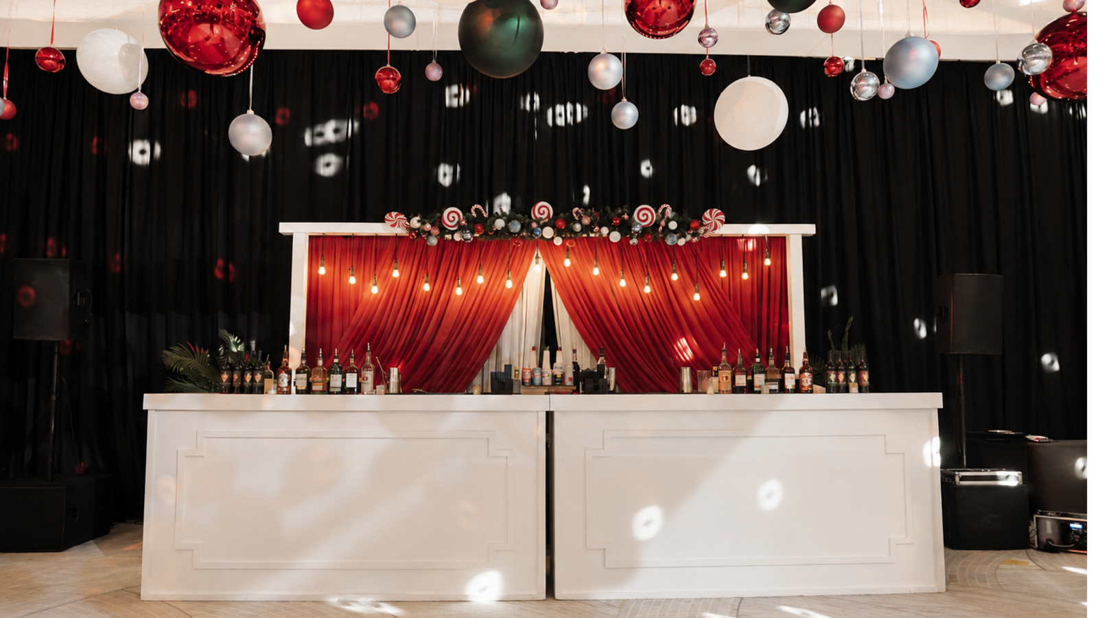 Elegant Cayman Islands wedding reception featuring dramatic red draping, chandeliers, floral arrangements, and festive hanging décor in a sophisticated ballroom.
