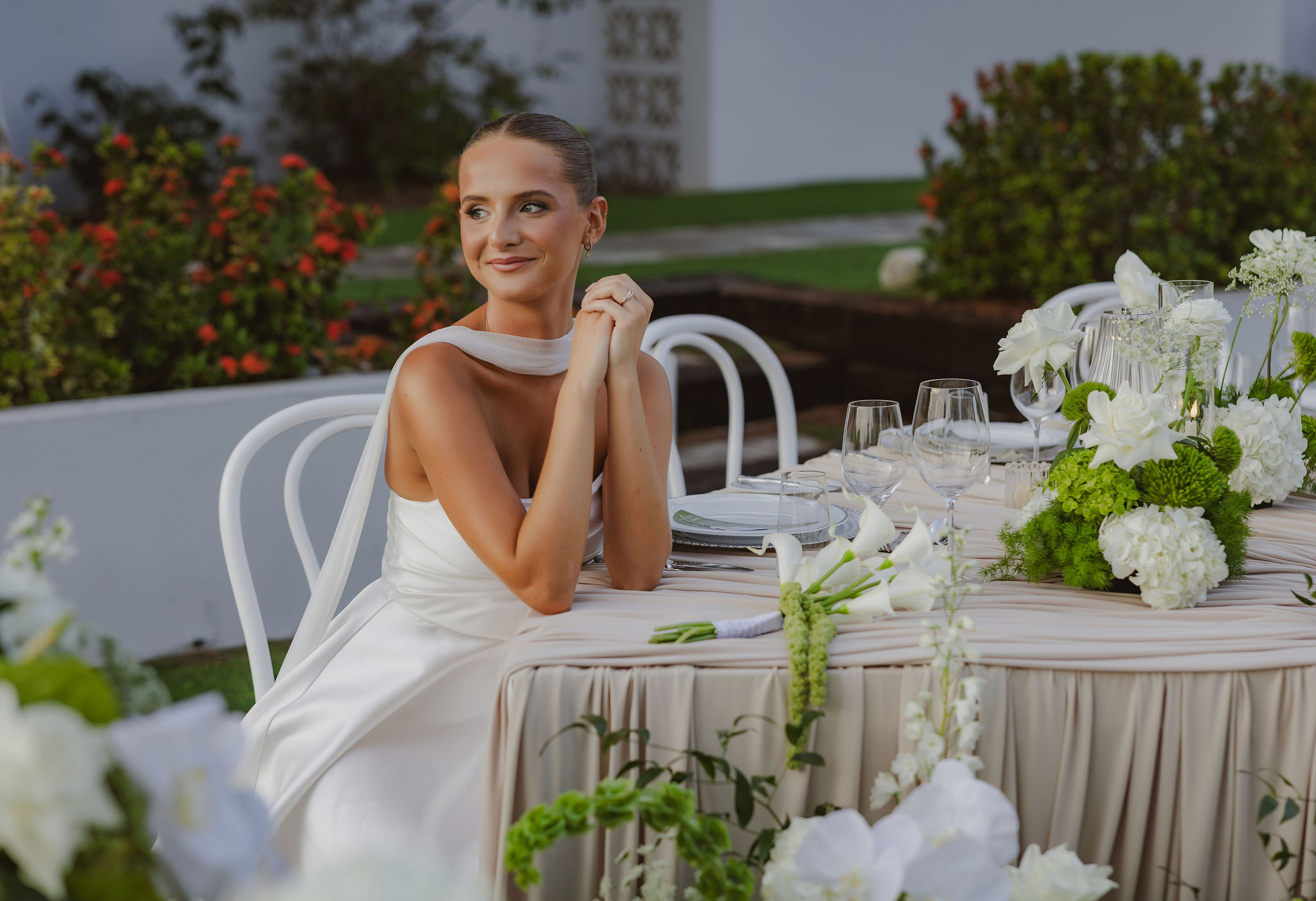 Bride in a white gown seated at a wedding reception table with white floral arrangements and greenery at the Westin.